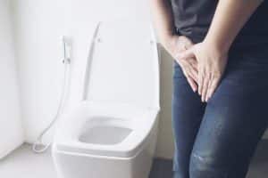Someone needing to pee while standing next to a toilet and bidet