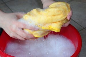 A person ringing out a soapy rag