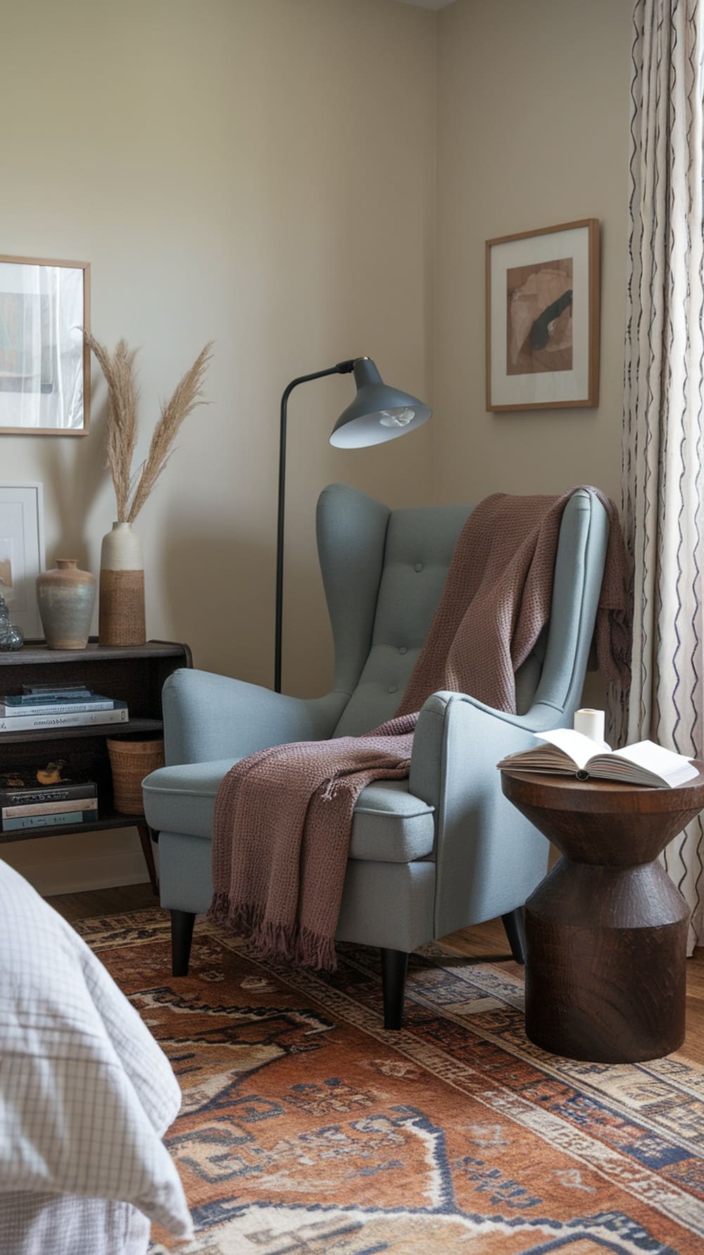 Cozy reading nook with a blue armchair, warm throw, and side table in an earthy dusty blue bedroom.