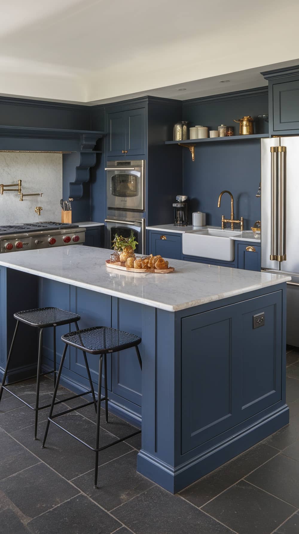 Modern navy blue kitchen with a marble island and black stools