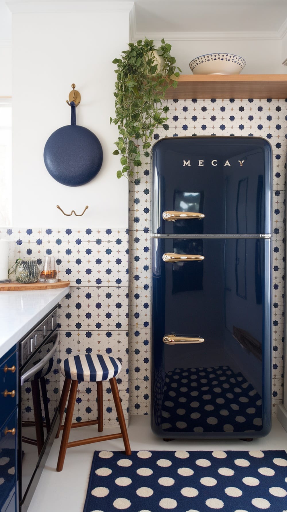 A stylish kitchen featuring navy blue cabinets and a matching refrigerator, accented with patterned tiles and a striped stool.