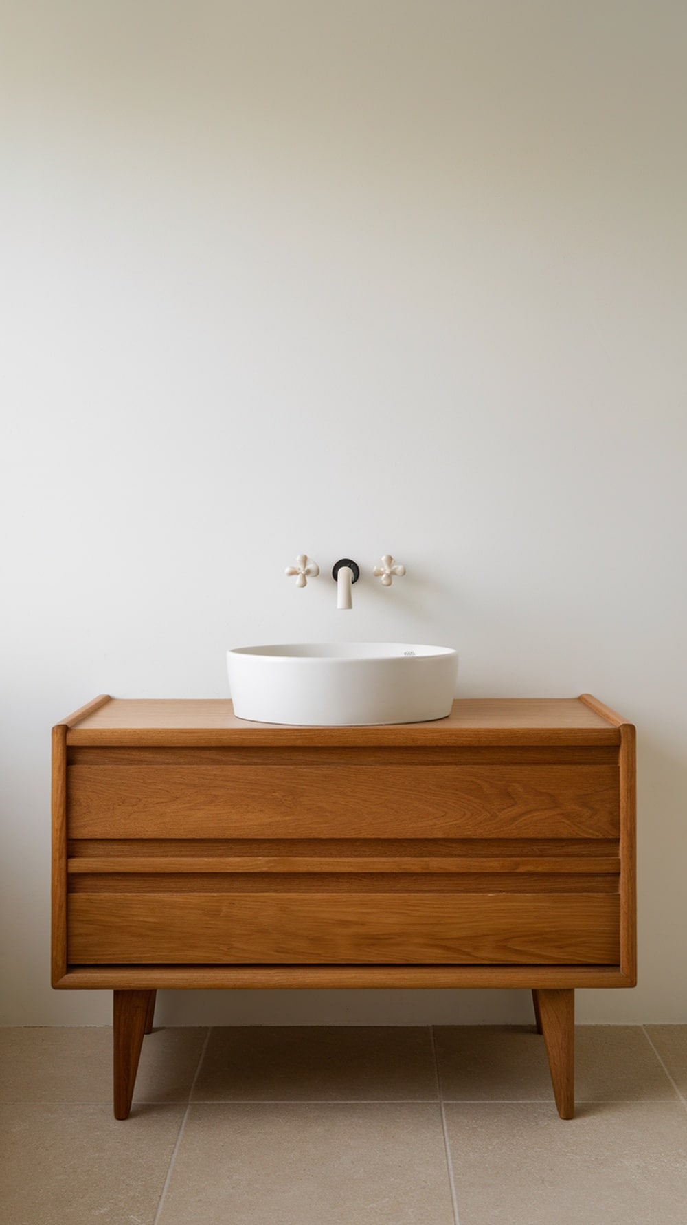 A minimalist wooden vanity with a round white sink and sleek black faucet in a modern bathroom.