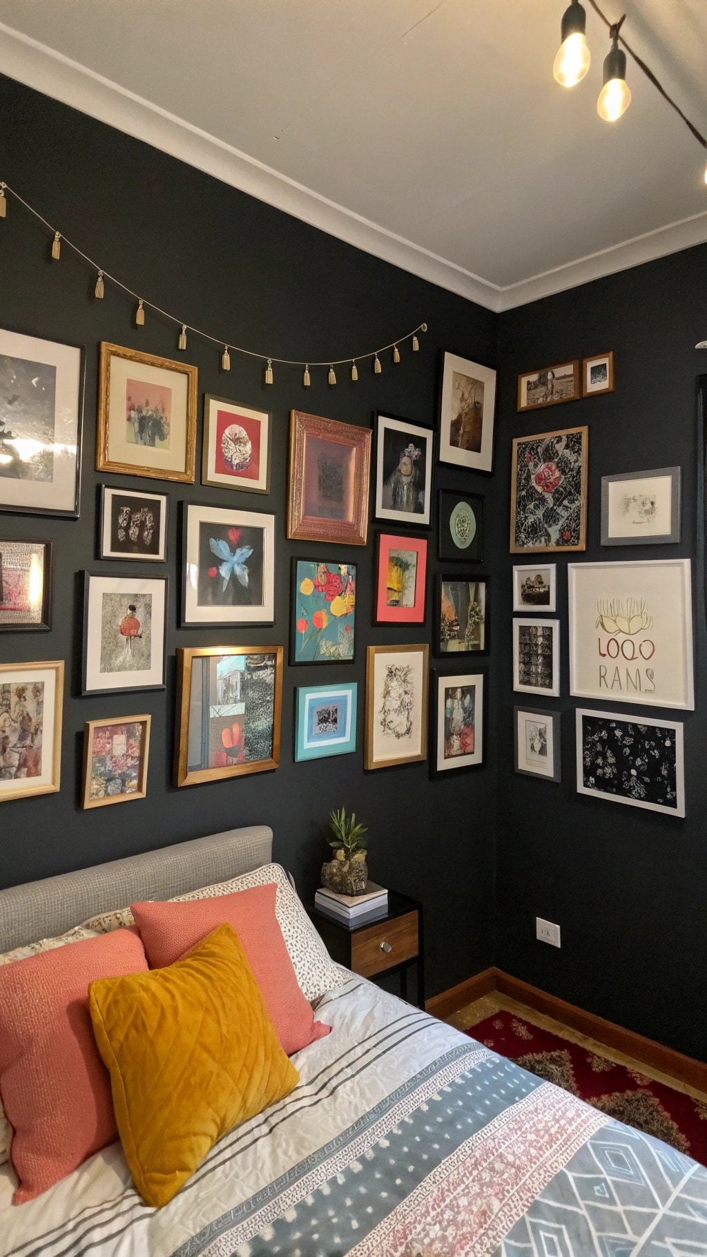 Eclectic gallery wall with various framed photos and artwork on a black wall in a bedroom.
